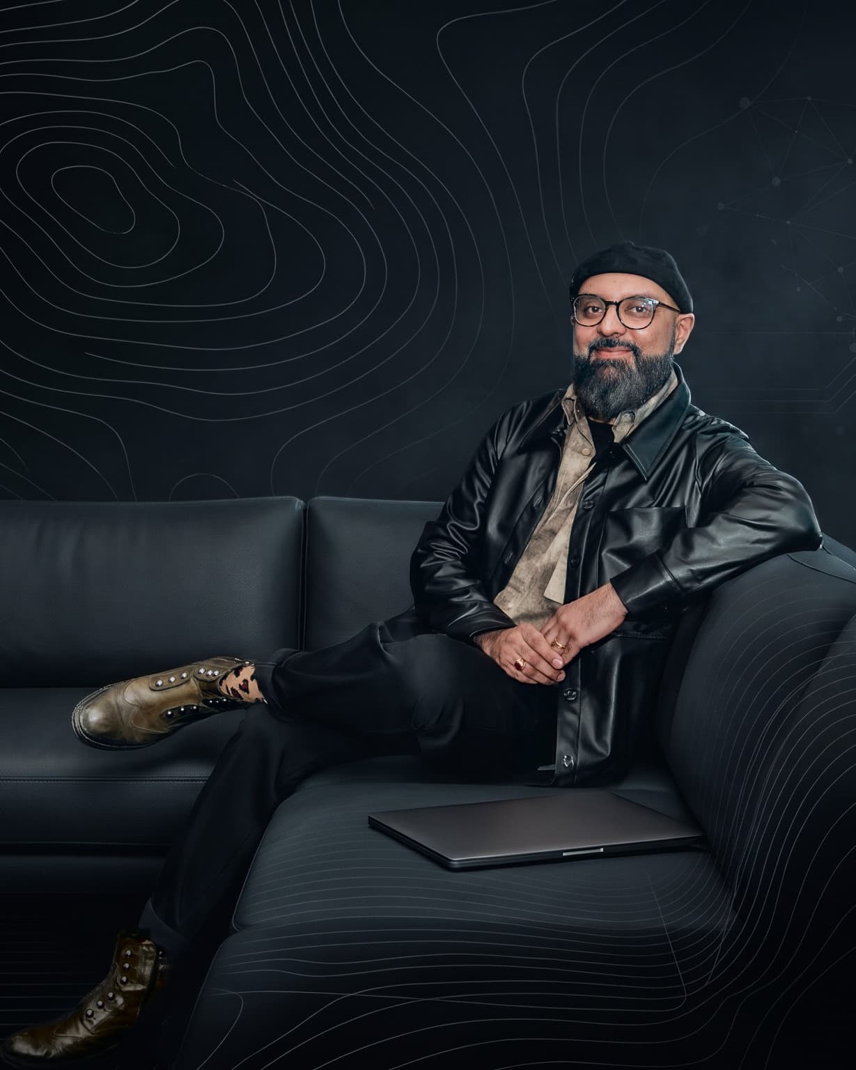 Mansur Mirani seated on a dark leather sofa, portrait crop